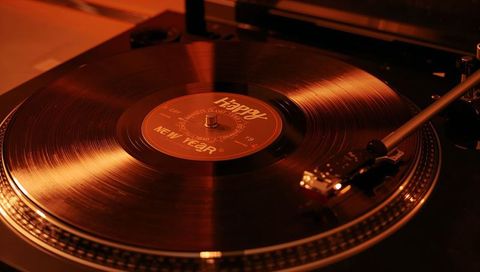 Spinning vinyl record celebrating new year on turntable with tonearm contacting grooves
