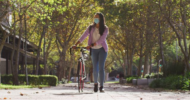 Asian woman wearing face mask with bicycle walking in the park. coronavirus covid-19 pandemic concept