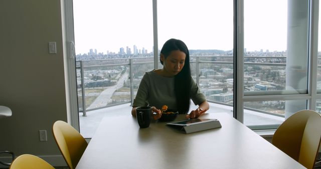 Young woman working on digital tablet at modern apartment with city view - Download Free Stock Images Pikwizard.com