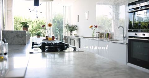 Modern Kitchen Interior with Marble Island and Gas Cooktop Against Greenery