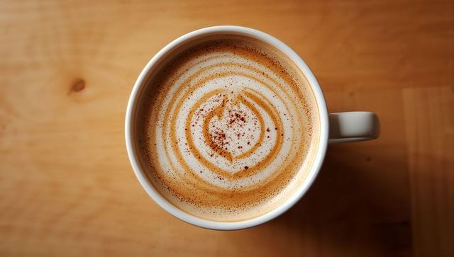 Top-Down Latte Swirl with Cinnamon Sprinkle on Warm Wooden Table