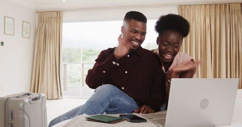 Couple Joyfully Planning Vacation at Home with Laptop