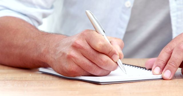 Man Writing Notes in Notebook at Wooden Desk - Download Free Stock Images Pikwizard.com