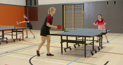 Women Competing in Intense Table Tennis Match in Gym