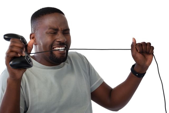 Frustrated man biting a wire of joystick against white background