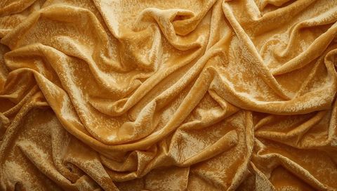 Golden crushed velvet fabric shimmering with rich draped folds and lush texture