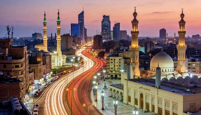 Dusk mosque domes and minarets glowing over city with curving light trails
