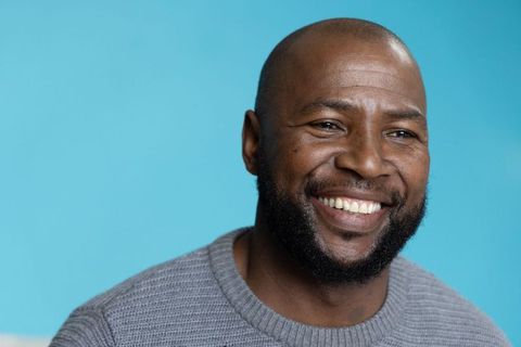 Confident smiling african american man wearing gray sweater against turquoise background