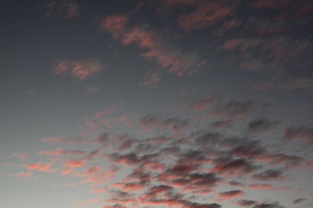 Depicting a serene evening sky, this image shows pink clouds gently lit during twilight. Ideal for use in backgrounds, screen savers, or in design projects needing a calm and atmospheric theme.