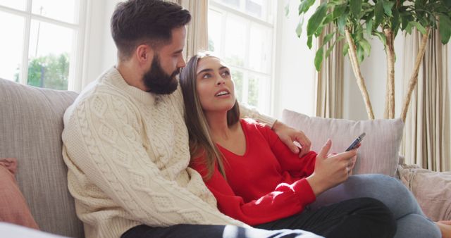 Image of happy caucasian couple siting on sofa and using smartphone - Download Free Stock Photos Pikwizard.com