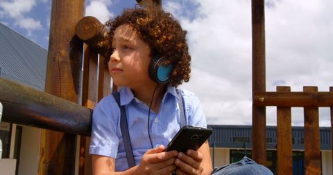 Young Boy Enjoying Music on Smartphone Outdoors
