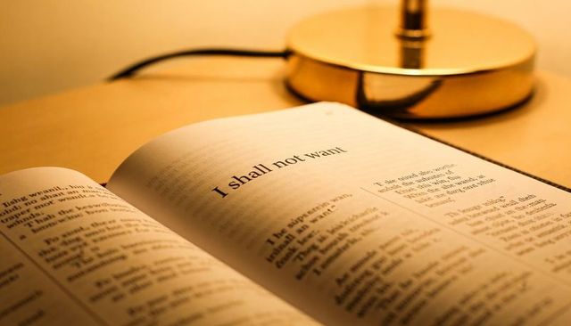 Reading psalm 23 'i shall not want' on open bible under warm lamp light, closeup devotional