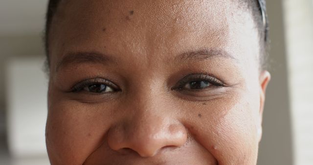 This close-up shows an African woman with a joyful and smiling expression. She has natural makeup and glowing skin. This image is great for promoting positivity, beauty, skincare products or articles focusing on happiness and wellbeing.