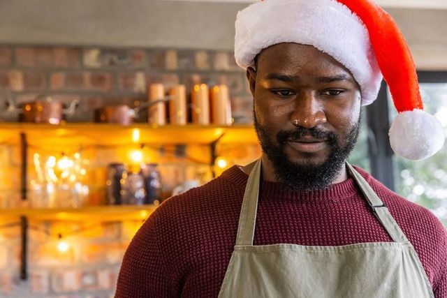 African american barista wearing santa hat serving holiday coffee in cozy rustic café