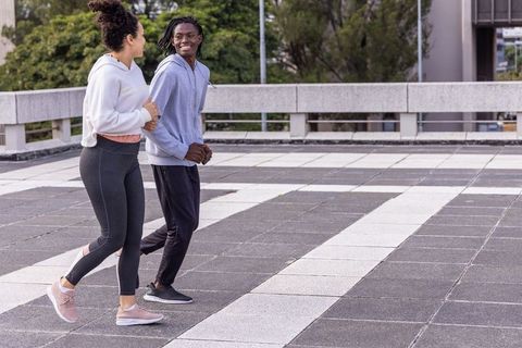 Diverse female friends walking and chatting on urban rooftop in activewear, smiling