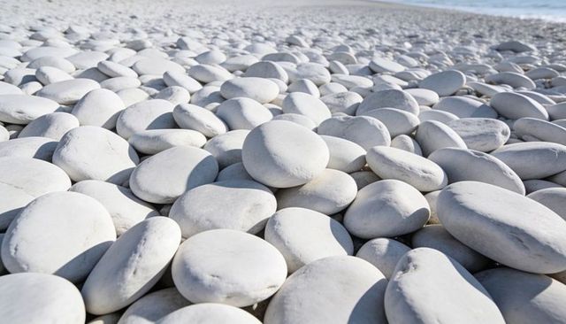 Lining white pebble beach with smooth round stones receding toward sea horizon