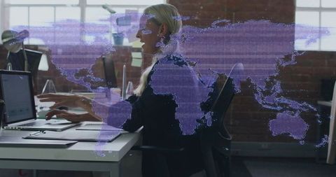 Blonde woman working on laptop with purple digital world map overlay in modern office
