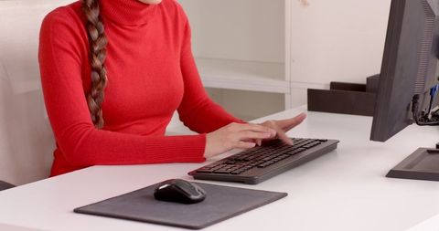 Woman in Red Sweater Typing on Keyboard at Modern Office Desk