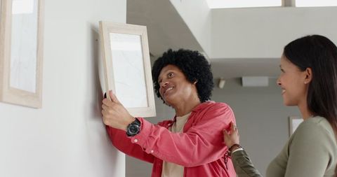 Couple hanging picture frame on living room wall