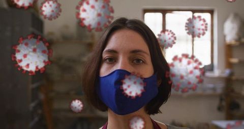 Artist wearing blue cloth mask in pottery workshop with covid-19 virus overlay concept