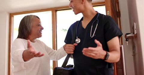 Caring male healthcare professional greeting senior woman at home