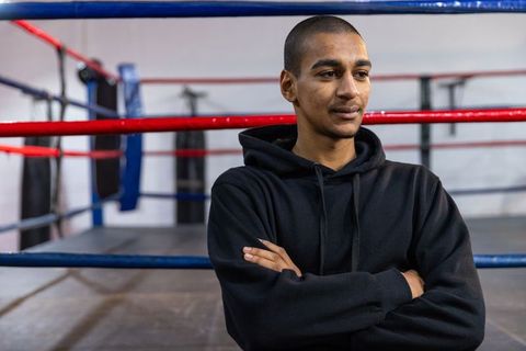 Young boxer standing in ring with arms crossed and focused expression