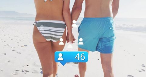 Couple walking hand in hand on sunny beach with notifications