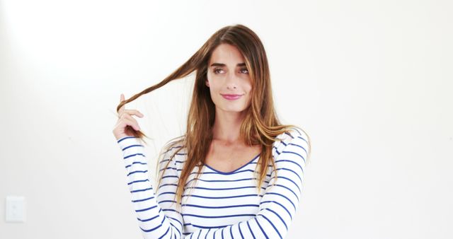 Young Woman with Long Hair Smiling Holding Hair Strand Indoors - Download Free Stock Images Pikwizard.com