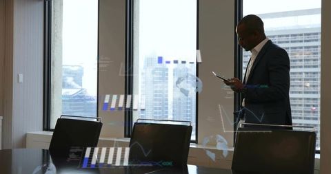 Executive standing by window using tablet in highrise conference room with city skyline