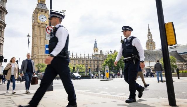 Police officers patrolling westminster crosswalk near elizabeth tower parliament
