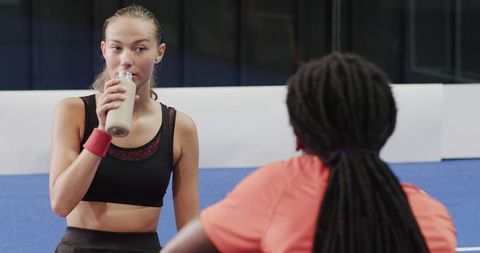 Young Woman Enjoying Smoothie Post Padel Tennis on Indoor Court