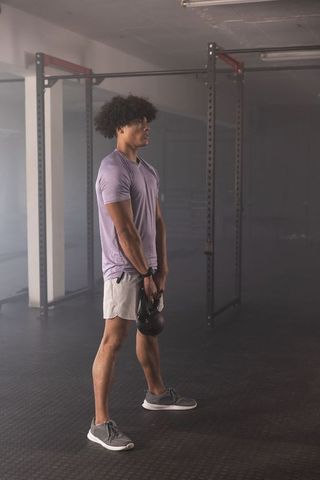 Performing kettlebell swing in moody industrial gym for strength training and conditioning