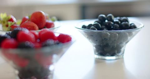 Backlit Blueberries Showing in Glass Bowl on Glossy White Countertop with Bokeh