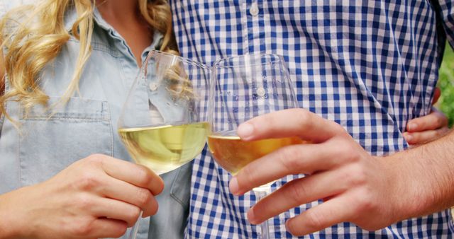 Couple raising wine glasses while sharing a moment of celebration and relaxation outdoors. Ideal for lifestyle blogs, social media posts, advertisements about wine, date ideas, or casual celebrations.