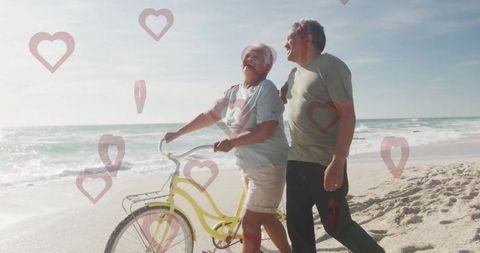 Senior couple enjoying relaxing beach walk with yellow bicycle