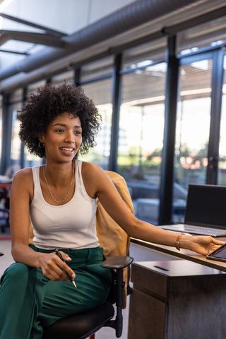 Professional woman using tablet and laptop in modern coworking space