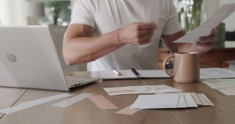 Man Working Paperwork Notes at Home Desk with Coffee