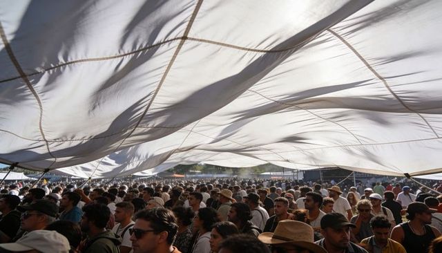 Crowd gathering under flowing fabric canopy at outdoor music festival