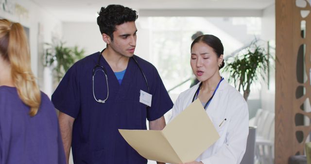 Image of happy, diverse male and female doctor with file talking in busy hospital corridor - Download Free Stock Photos Pikwizard.com