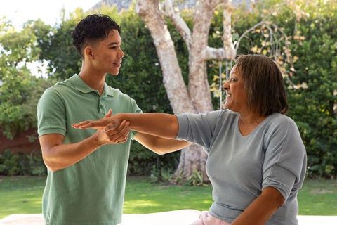 Senior woman assisted by male caregiver during outdoor rehab