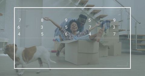 Couple moving into new home packing boxes, woman in box laughing while partner pushing, dog running