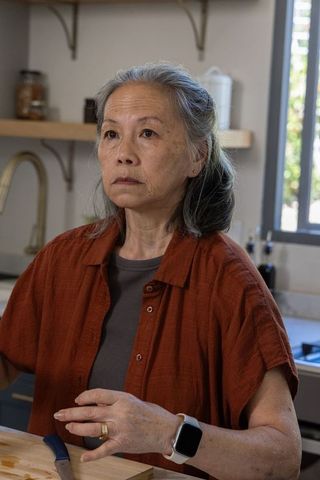 Senior asian woman preparing vegetables on cutting board wearing smartwatch in kitchen