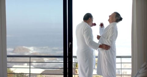 Senior Couple Enjoying Ocean View Balcony with Refreshments
