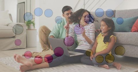 Family trio enjoying laptop on living room rug with colorful circular overlays
