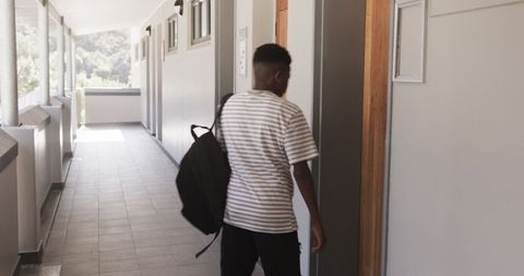 Teenage Student Walking Down School Corridor Carrying Backpack