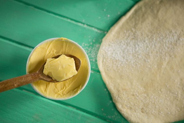 Overhead view of butter in bowl by rolled dough on table