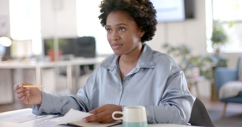 Focused Businesswoman Holding Pen in Modern Office Environment