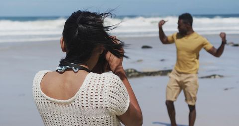 Woman Photographing Partner on Sandy Beach Vacation
