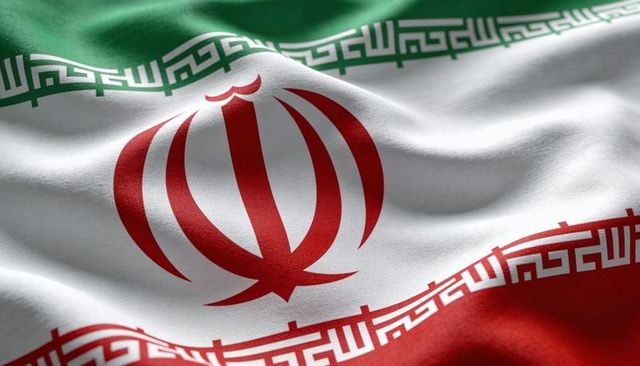 Waving iranian flag closeup showing emblem and kufic script on textured tricolor fabric