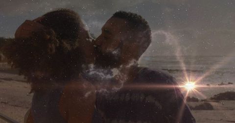 Couple kissing amidst stunning sunset beach scene and cosmic overlay